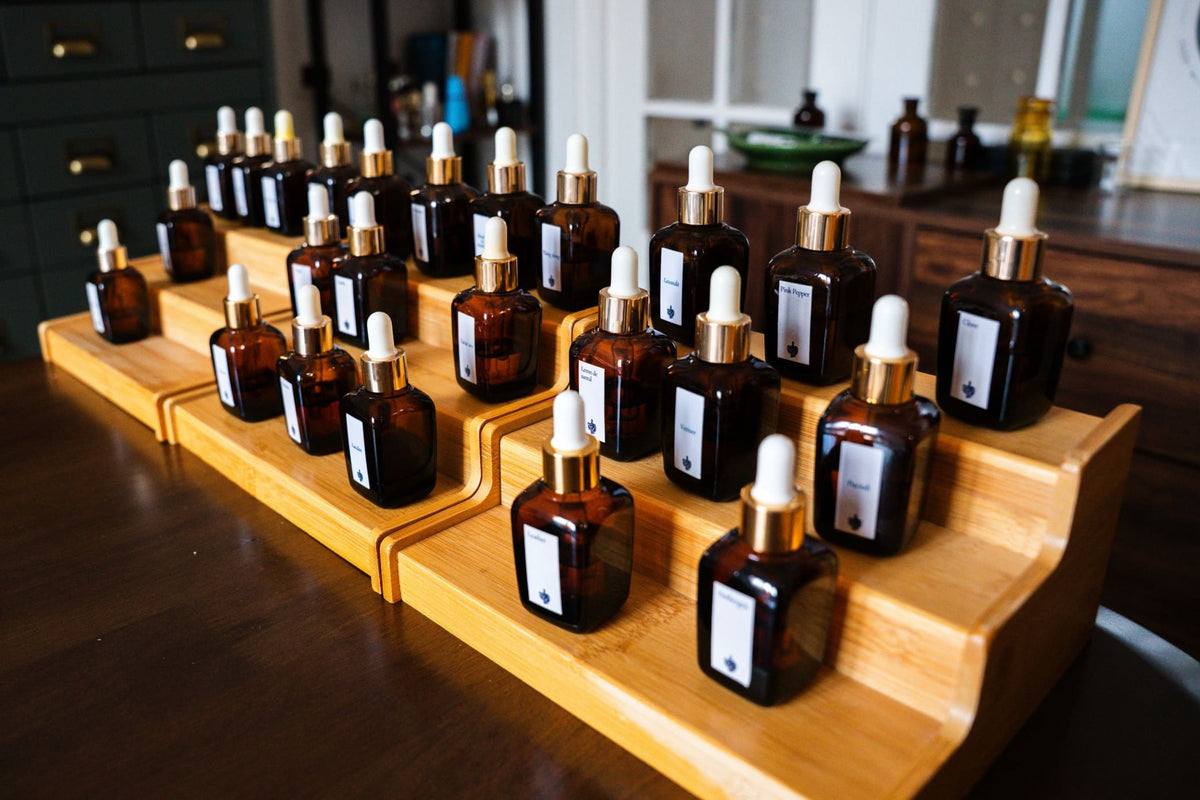 Esențe pe suportul de lemn la atelierul de parfum, cu etichete precum Pink Pepper, Lavandă și Vetiver