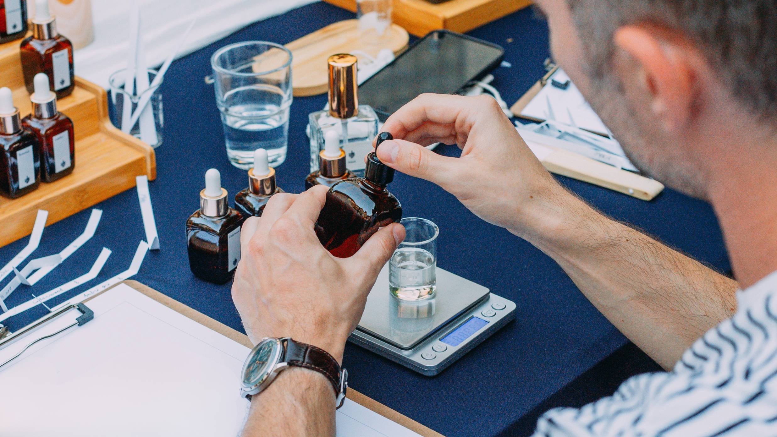 Participant la atelier de parfum deschide o sticluță cu esență deasupra paharului gradat de pe cântar