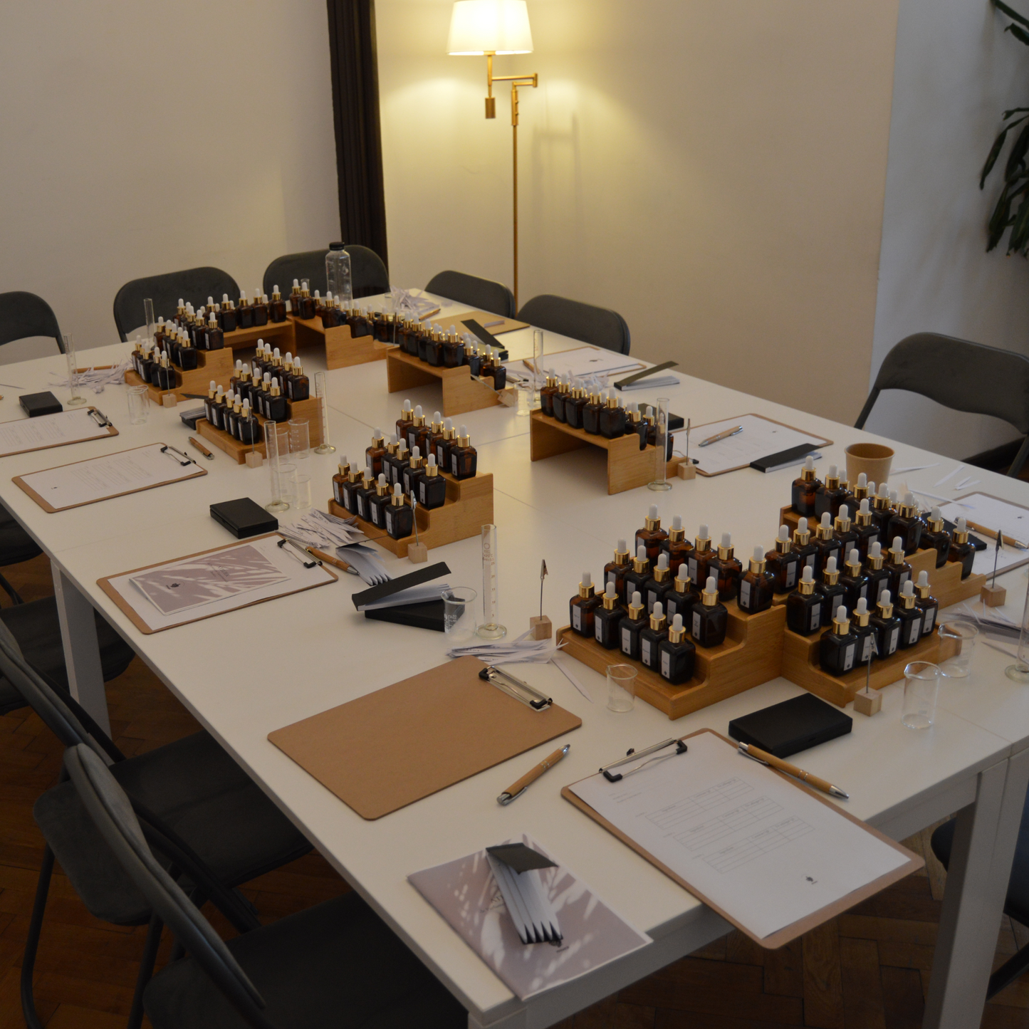 Masă de lucru cu sticle, ingrediente parfumate și pipete, pregătită pentru un atelier de creație olfactivă