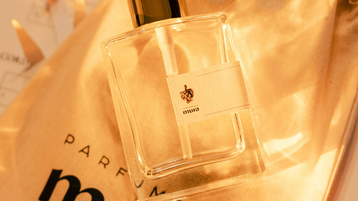 Sticlă de parfum personalizat cu eticheta Parfumeria Mura, așezată pe săculețul de pânză cu logo-ul brandului