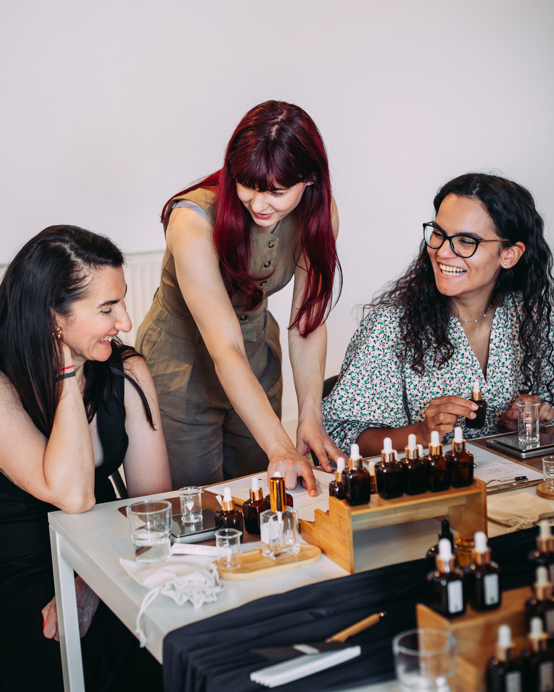 Două participante la atelierul de parfum urmăresc explicațiile trainerului despre cum să își creeze propriul parfum