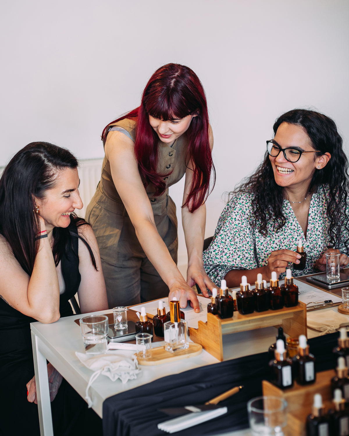 Două participante la atelierul de parfum urmăresc explicațiile trainerului despre cum să își creeze propriul parfum
