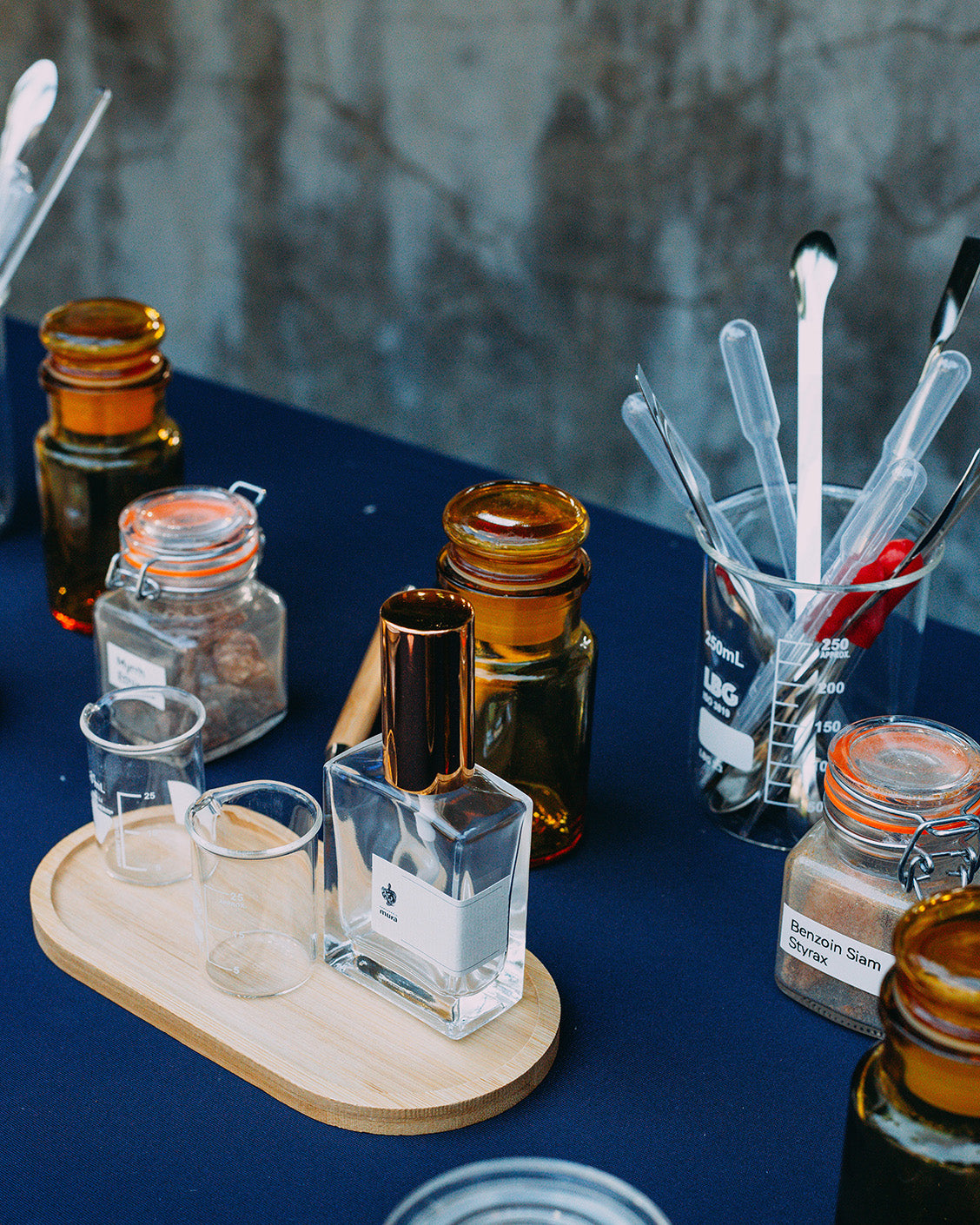Masa de lucru a atelierului pe care se află materii prime, instrumente și sticluța de parfum personalizat Mura
