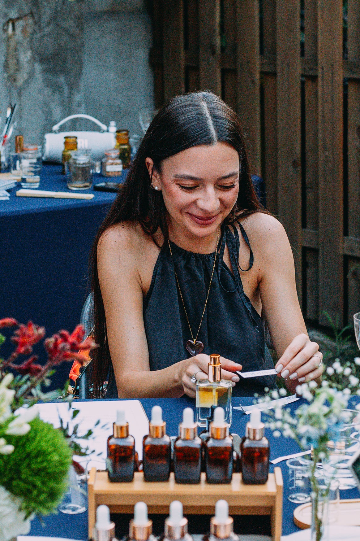 Participantă zâmbind la atelierul de parfum în aer liber, în București, cu sticluța de parfum umplută în față