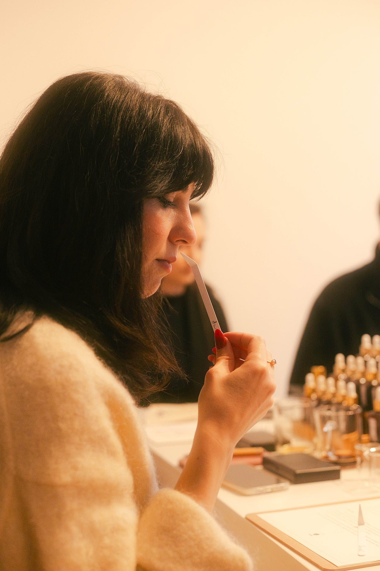 Participantă din profil miroase un blotter la atelierul de parfum, în lumina caldă a sălii