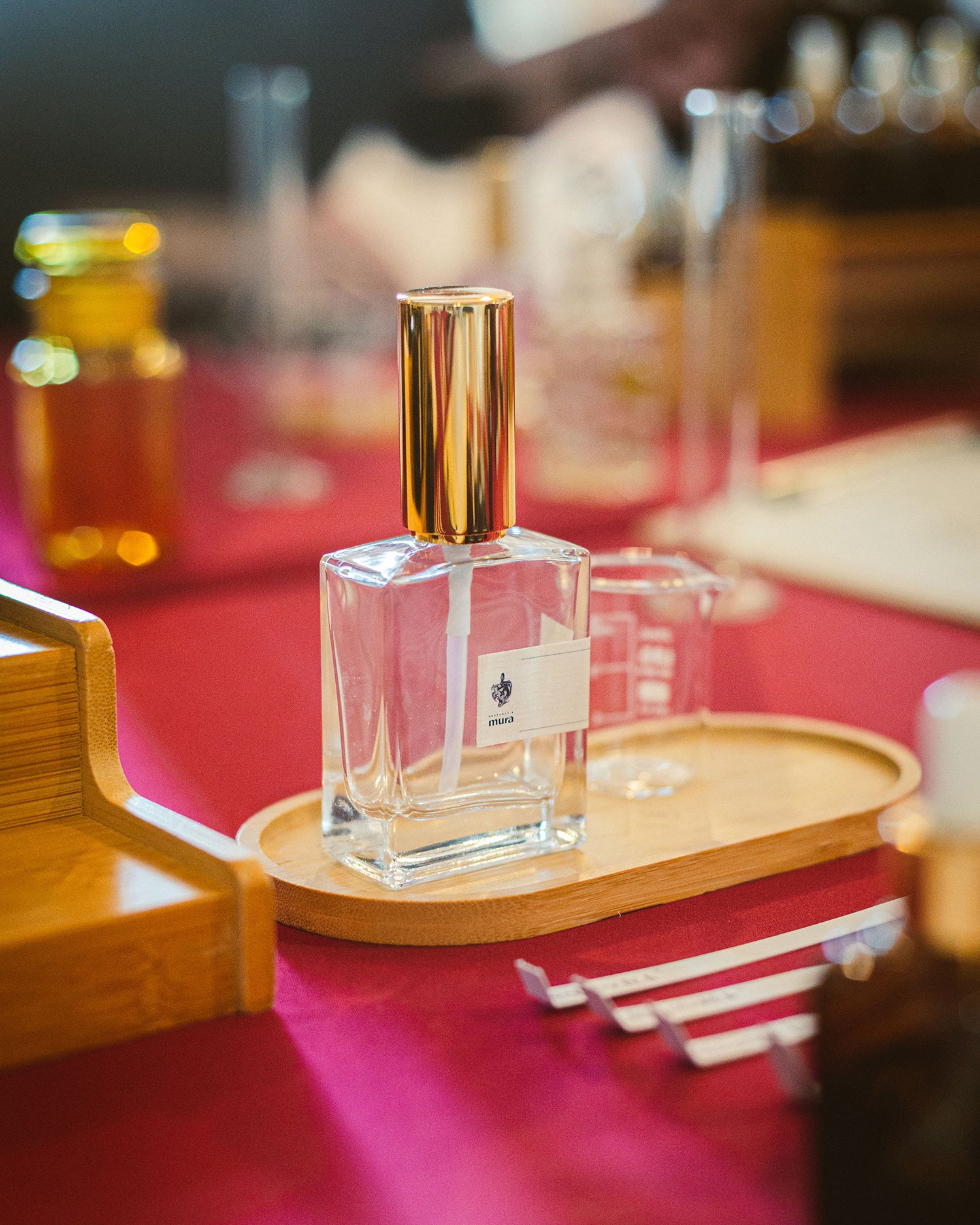 Sticluța de parfum personalizat Parfumeria Mura cu pulverizator auriu, pe tăvița de lemn a atelierului