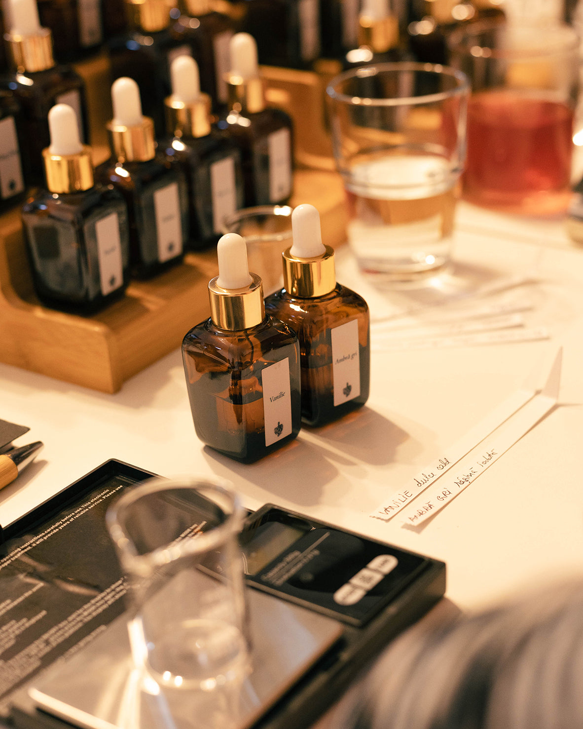 Sticluțele cu esențele Vanilie și Ambră gri, lângă blottere scrise de mână, la atelierul de parfum