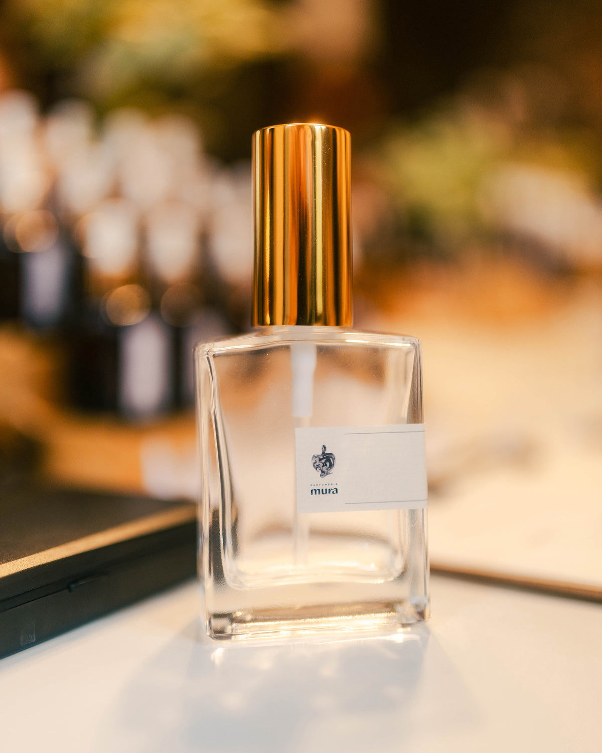 Sticluță de parfum personalizat Parfumeria Mura cu pulverizator auriu, pe masa atelierului