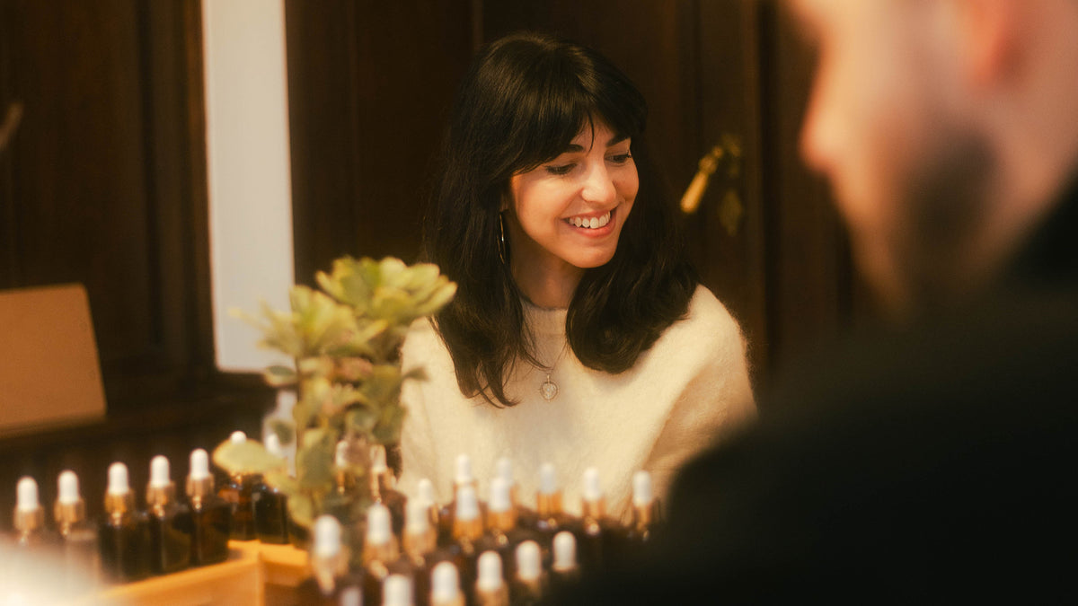 Participantă zâmbind la un atelier de parfum Parfumeria Mura, în fața suportului cu esențe