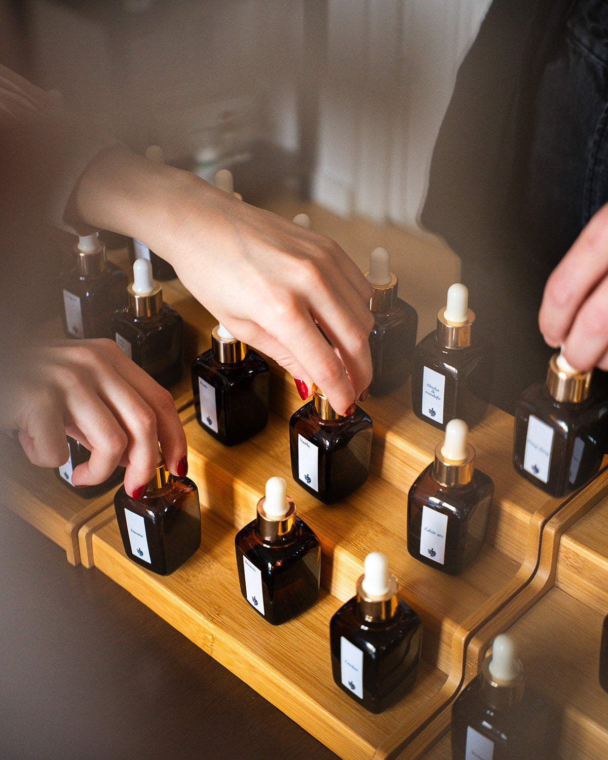 Doi participanți aleg în același timp esențe de pe suportul de lemn, la atelierul de parfum